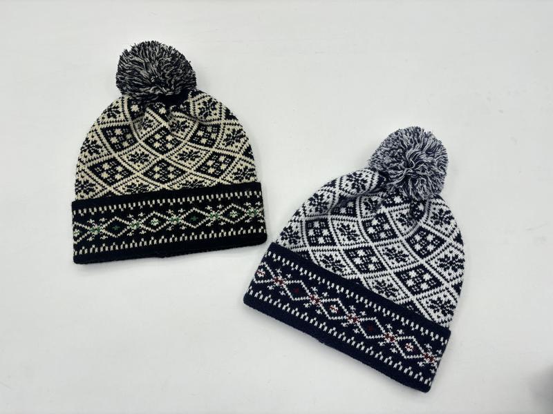 Two Fair Isle knit pom pom beanies in black-cream and navy-white Nordic snowflake pattern on white background
