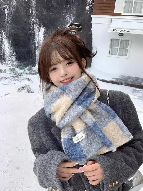 Young woman wearing a cozy blue and cream plaid oversized fluffy scarf in a snowy outdoor winter setting