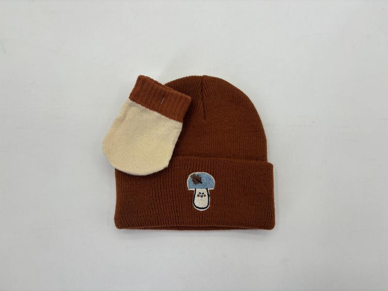 Brown ribbed knit winter beanie hat with small embroidered patch, paired with cream and brown two-tone knit mitten