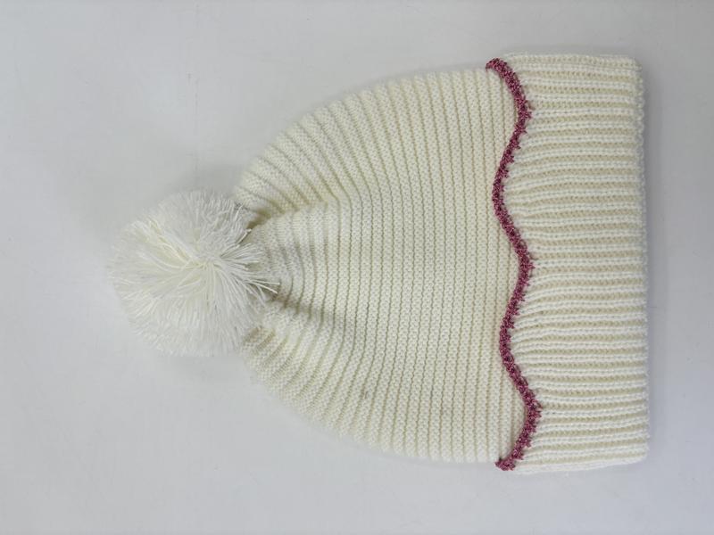 Cream chunky ribbed knit winter beanie hat with fluffy pom-pom top and decorative pink zigzag stitch trim at brim