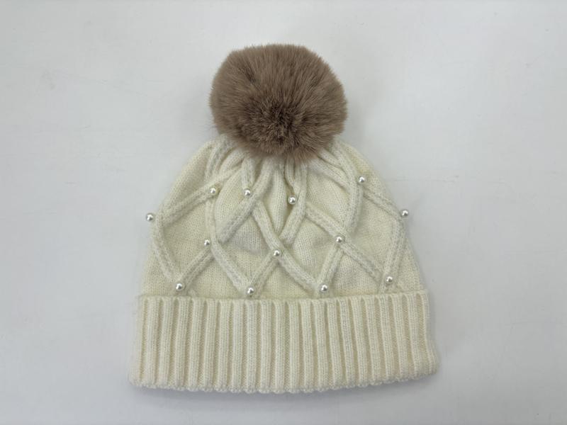 Cream cable knit winter beanie with pearl bead accents, ribbed cuff, and large taupe faux fur pom-pom on top