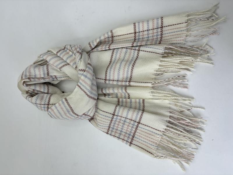 Cream woven plaid scarf with blue, pink, and brown stripes, twisted fringe ends, laid flat on white background
