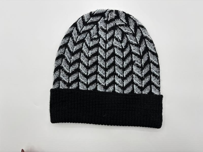 Black and grey chevron herringbone pattern knit beanie hat with folded ribbed cuff, laid flat on white background