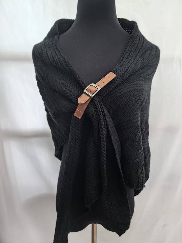 Black cable knit wrap shawl displayed on mannequin, fastened with a tan leather buckle clasp at the chest