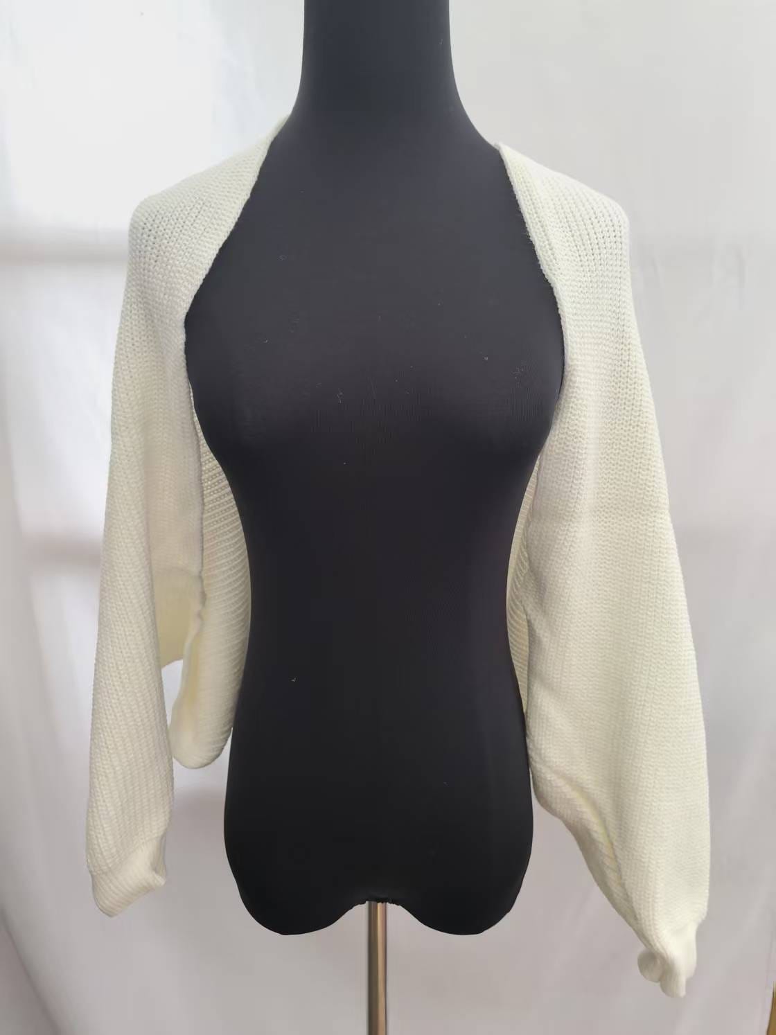 Cream chunky knit open front bolero shrug with long sleeves displayed on a black dress mannequin against white background