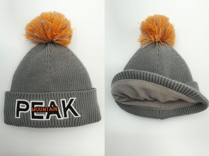 Grey chunky knit winter beanie with orange pom-pom, embroidered block letter patch, and soft fleece inner lining shown front and interior views