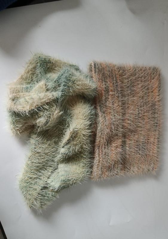 Two eyelash yarn knit fabric swatches in sage green and dusty rose peach tones laid on white surface