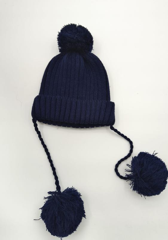 Navy blue ribbed knit winter beanie with top pom-pom and two long braided ties ending in large pom-poms