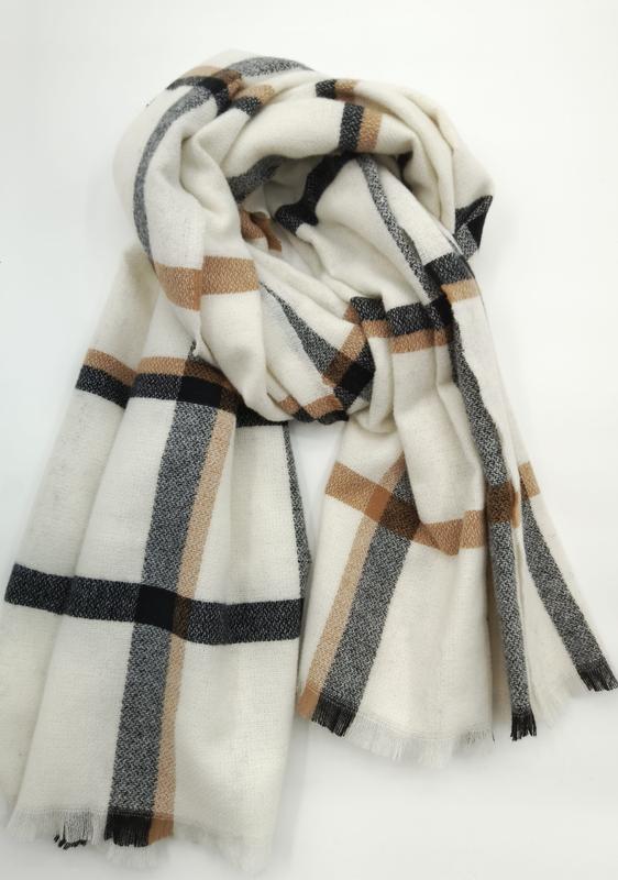 Cream white oversized blanket scarf with black and camel brown plaid check pattern, folded and draped on white background