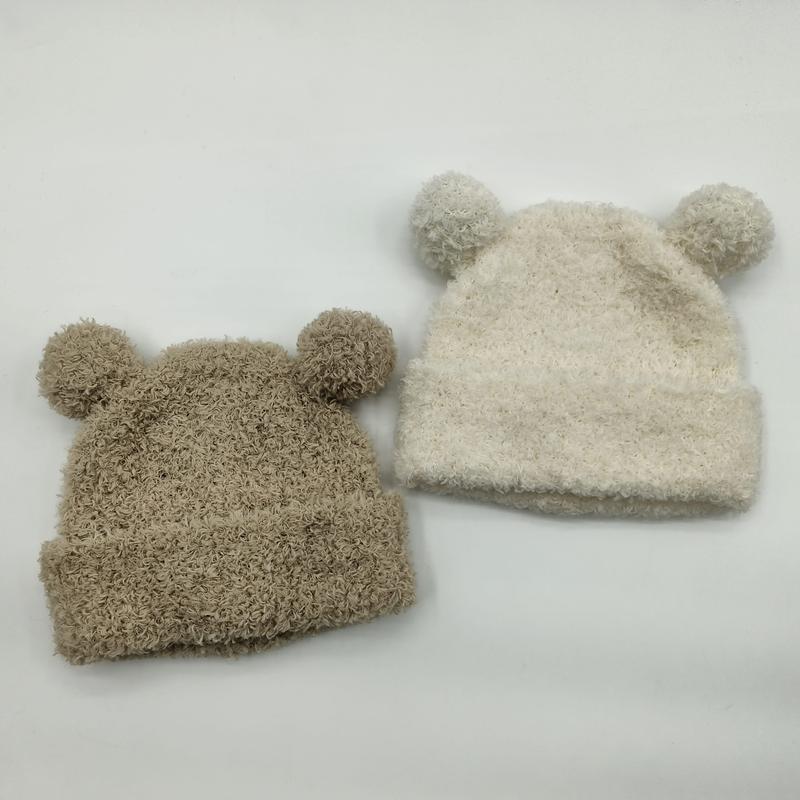 Two fuzzy knit baby beanies with bear ears and pom-poms in beige and cream colors on white background