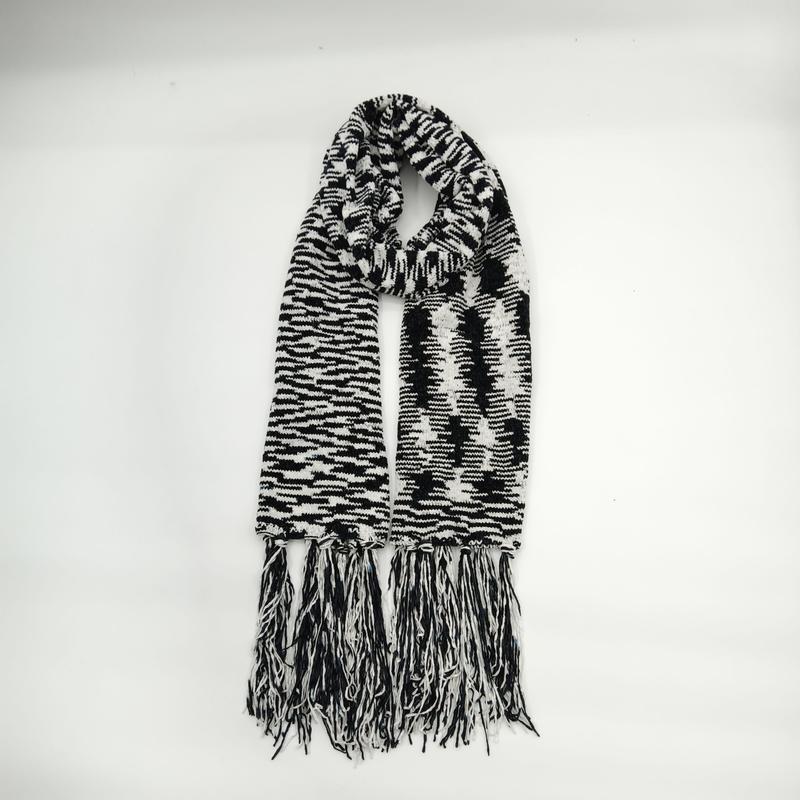 Black and white houndstooth patterned knit scarf with long mixed fringe tassels displayed folded on white background