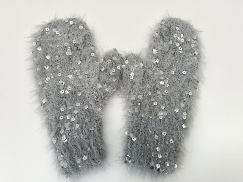 Pair of grey fluffy eyelash yarn mittens with silver sequin embellishments laid flat on white background