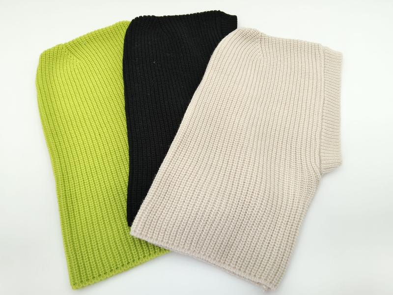 Three folded chunky ribbed knit sleeveless vest tops in lime green, black, and beige laid on white background