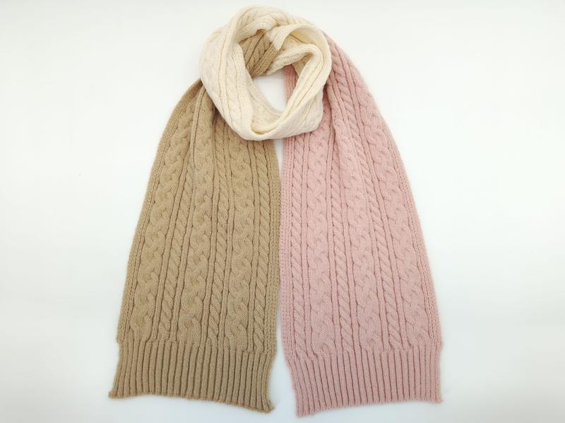 Cable knit scarf with beige and pink ends twisted into a cream center loop, displayed flat on white background