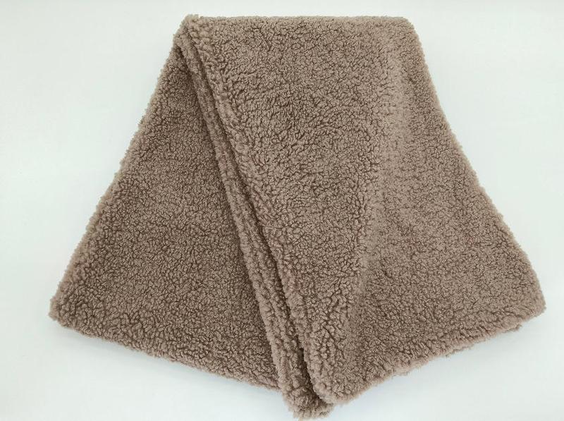 Folded taupe sherpa fleece throw blanket with curly textured pile and finished edges on white background