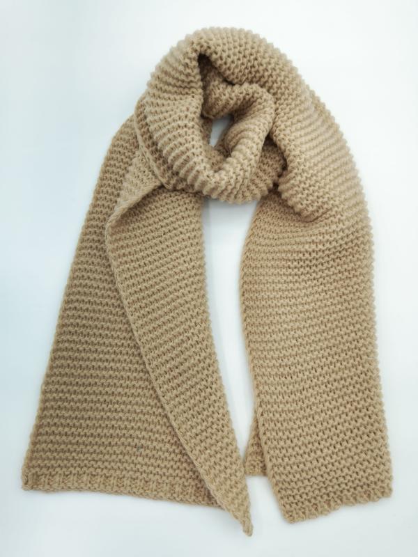 Camel beige chunky knit winter scarf looped and draped flat lay on white background showing textured garter stitch pattern