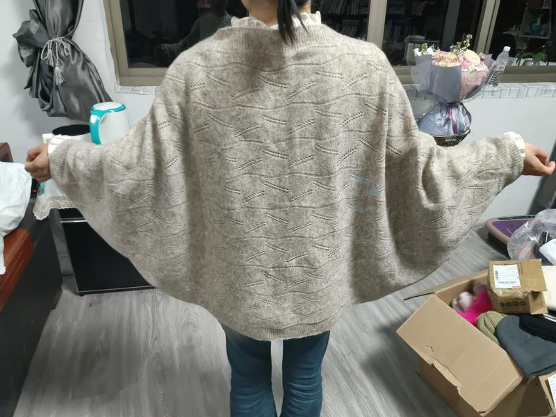 Woman wearing oversized beige batwing sleeve knit sweater with diamond pointelle pattern, shown from the back, paired with blue jeans