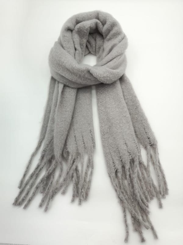 Light grey cozy knit winter scarf looped and displayed flat, featuring long fringe tassels on both ends, on white background