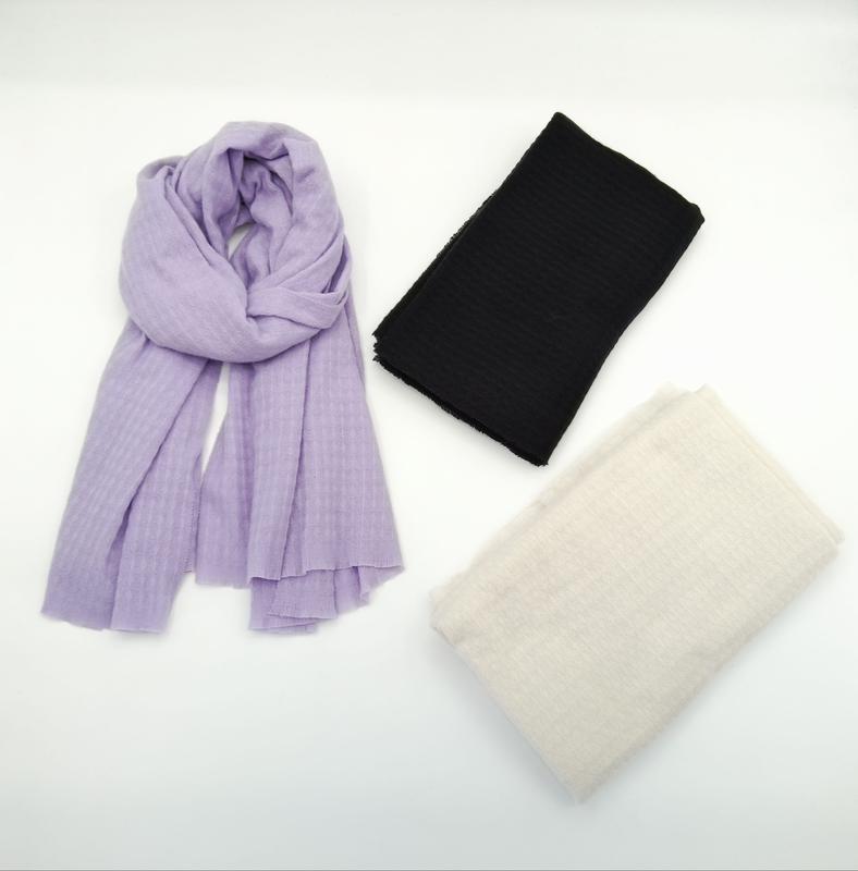 Three lightweight ribbed scarves displayed on white background: one draped in lavender, one folded in black, one folded in cream