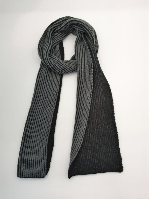 Two-tone ribbed knit scarf in grey and black, looped and draped flat on white background showing texture