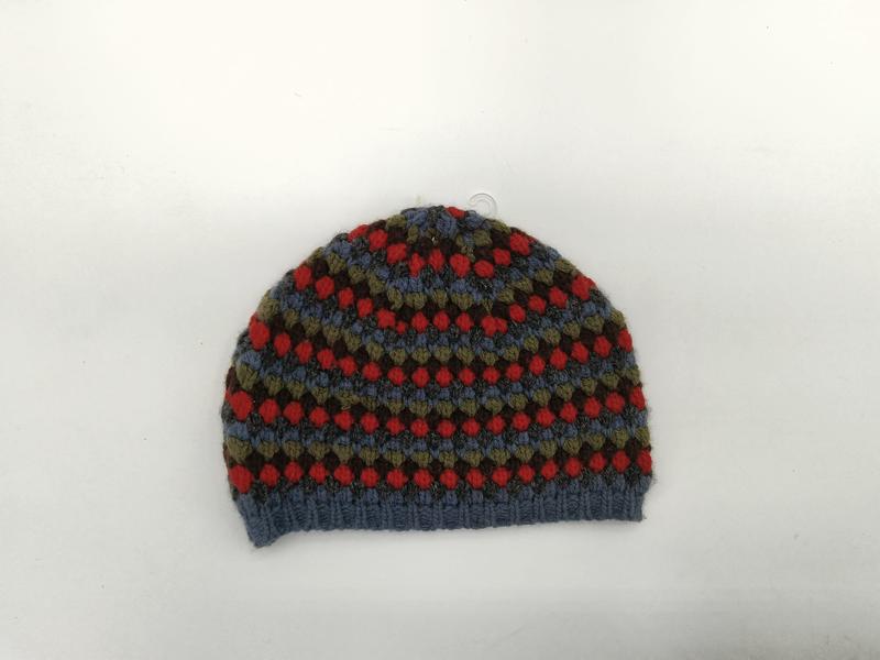 Handknit beanie hat with Fair Isle pattern in blue, red, olive, and brown on white background