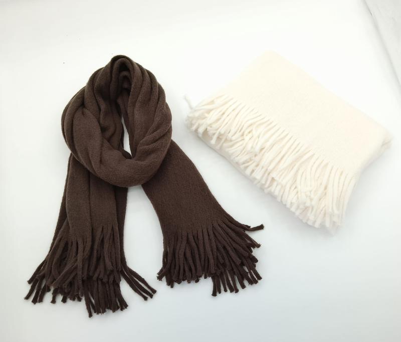 Brown twisted fringed scarf and folded cream fringed shawl wrap displayed on white background