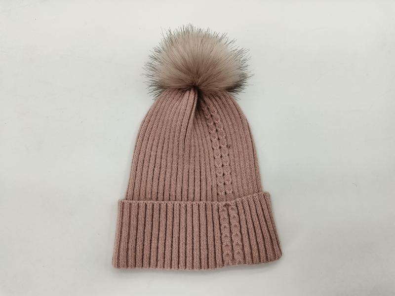 Blush pink ribbed knit winter beanie hat with large faux fur pom pom on white background