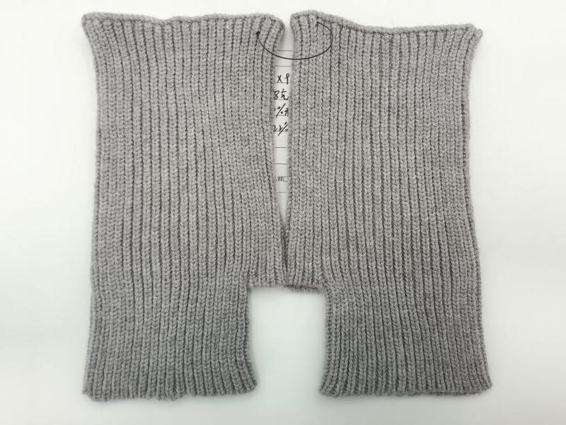Pair of light gray ribbed knit fingerless gloves laid flat on white background, showing fine rib texture and open finger design