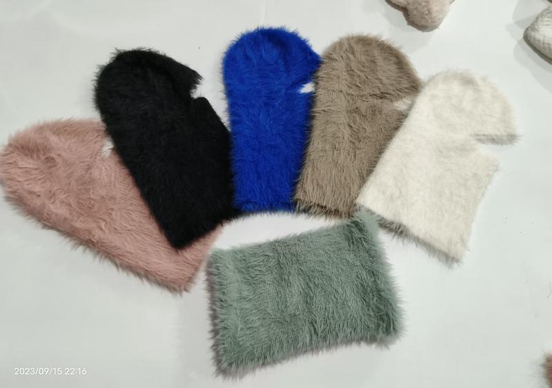 Six fluffy faux fur balaclava hats arranged in a fan layout in pink, black, blue, taupe, cream, and sage green colors