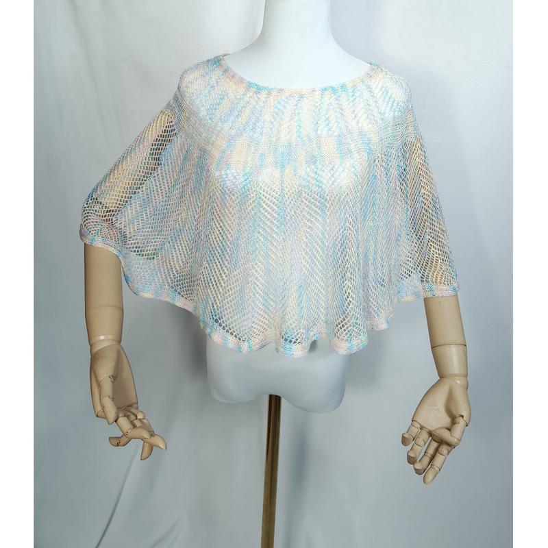 White mannequin wearing a sheer open-knit mesh poncho in pastel blue, peach, and ivory with a loose drape fit