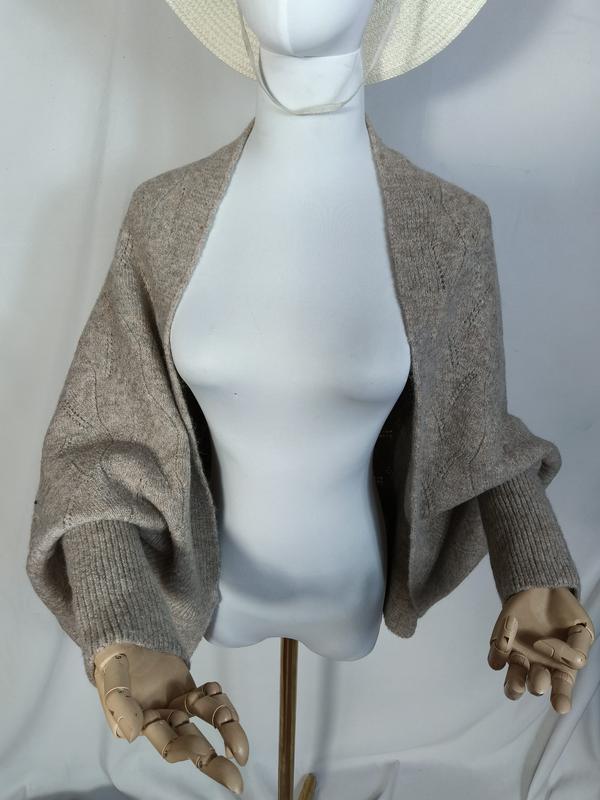 Taupe knit open-front shrug with balloon sleeves and ribbed cuffs displayed on a mannequin