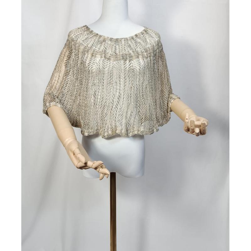 Beige and gold metallic open-knit crochet cropped poncho top displayed on a white mannequin with wooden articulated hands