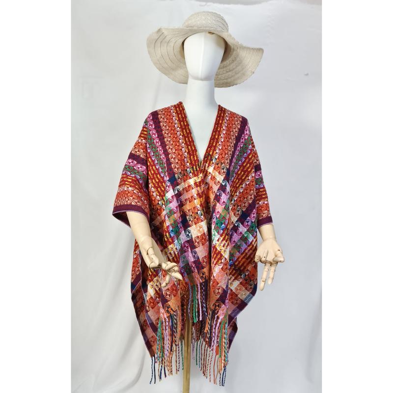 Multicolor handwoven geometric pattern open-front poncho with colorful fringe hem displayed on mannequin with wide-brim hat