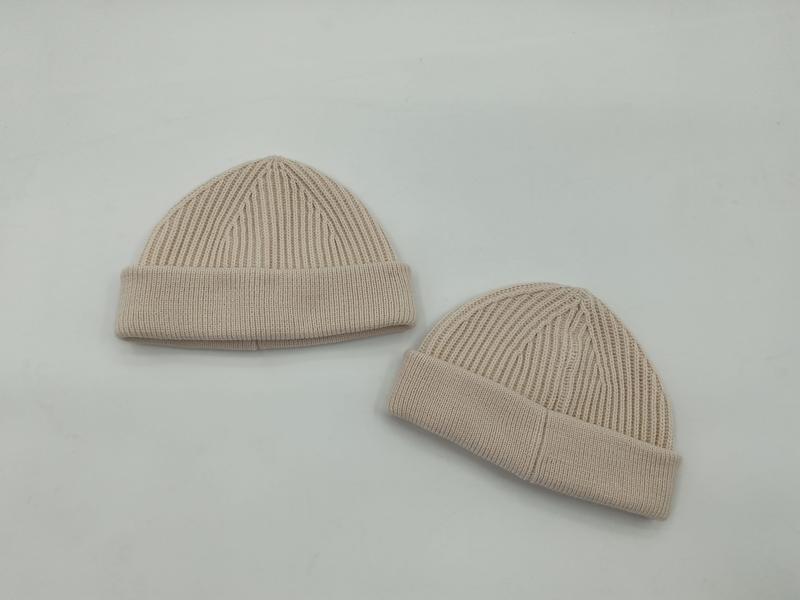 Two beige ribbed knit cuffed beanie hats displayed flat on a white background, showing different sizes