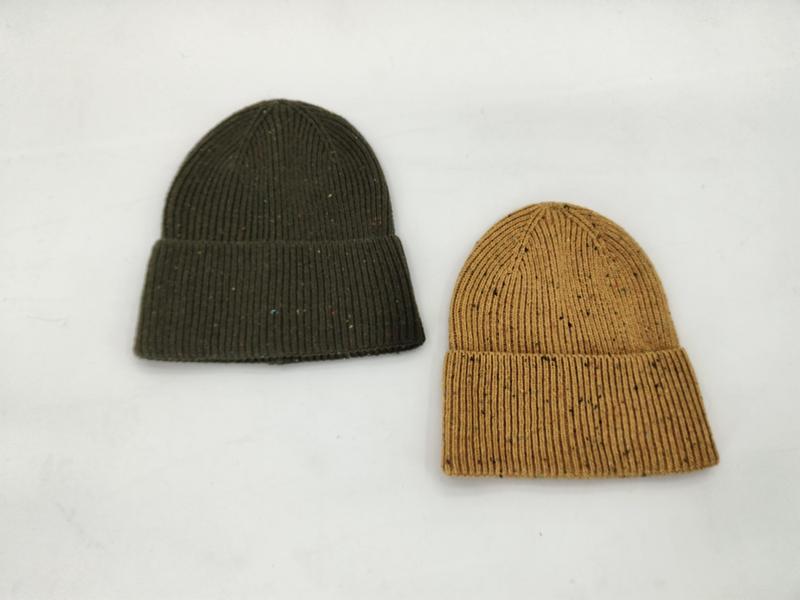 Two ribbed knit beanies with speckled yarn laid flat, one in olive green and one in mustard yellow, on white background