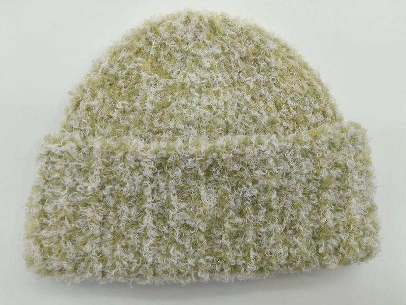 Sage green and cream boucle knit beanie hat with folded cuff, curly textured yarn, on white background