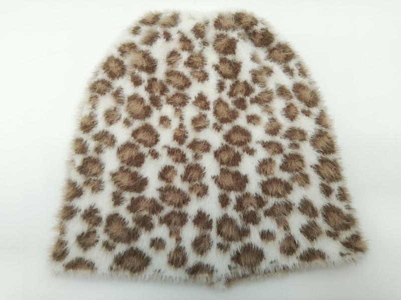 Close-up of soft faux fur fabric swatch with brown leopard spot pattern on cream white background