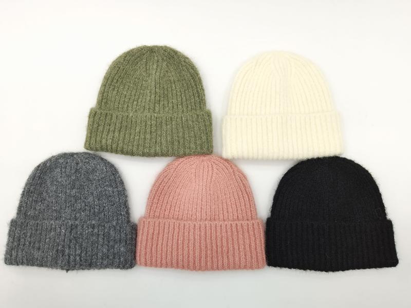 Five ribbed knit beanies in olive green, cream, gray, blush pink, and black arranged on white background