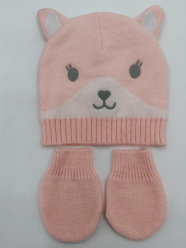 Pink knitted baby beanie hat with bear ears and face design paired with matching mittens set on white background