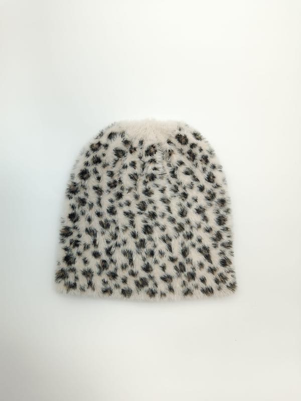 Flat lay of a fluffy ivory beanie hat with black and brown leopard spot print pattern on white background