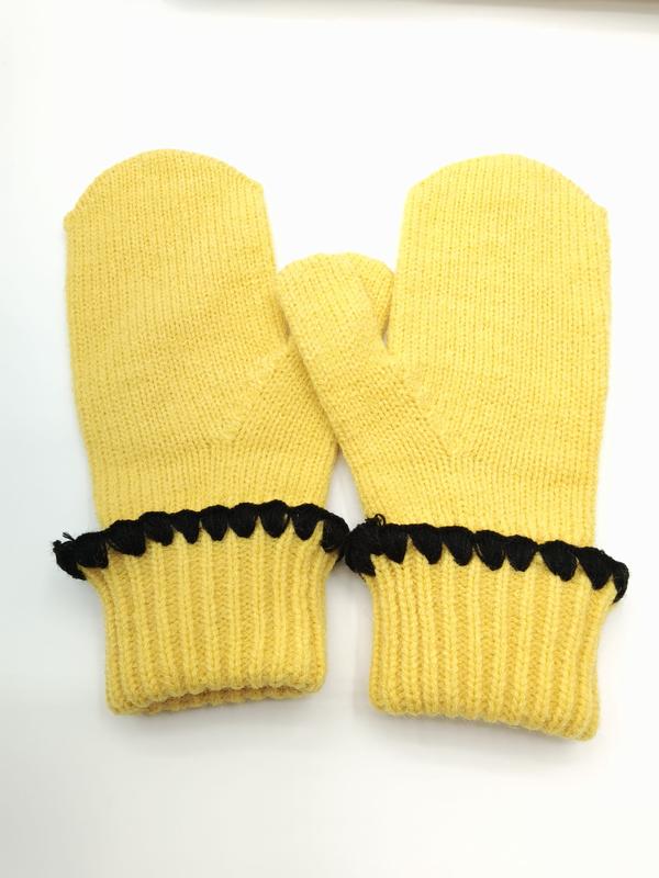 Pair of yellow knitted winter mittens with black scalloped crochet trim along the ribbed cuff, laid flat on white background