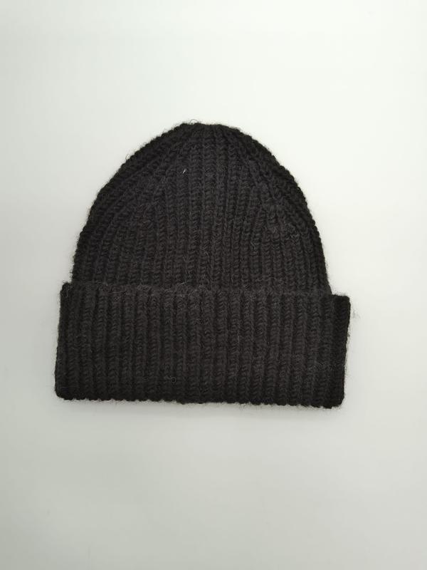 Black chunky ribbed knit beanie hat with folded cuff, laid flat on white background, handcrafted wool blend