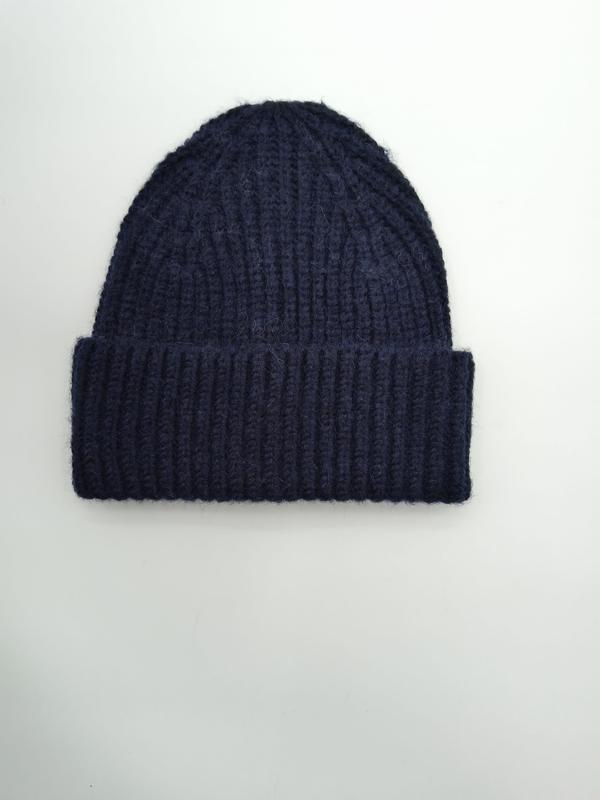 Navy blue chunky ribbed knit winter beanie hat with folded cuff, laid flat on white background