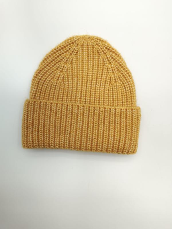 Mustard yellow chunky ribbed knit winter beanie hat with folded cuff laid flat on white background