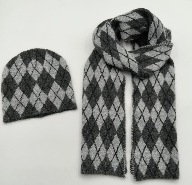 Matching dark grey and light grey argyle knit beanie hat and long scarf set laid flat on white background
